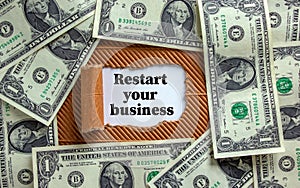 The text `restart your business` appearing behind torn brown paper. Dollar bills. Business concept