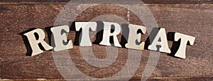 text RETREAT from wooden letter alphabet in the sun on a sunny day