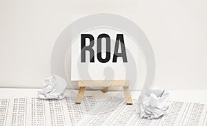text return on assets ROA on easel with office tools and paper.Top view. Business concept