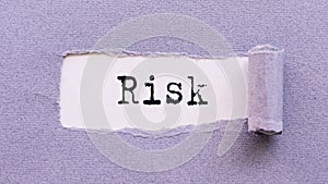 The text RISK appears on torn lilac paper against a white background