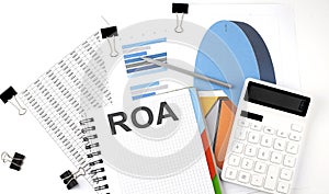 Text ROA on a notebook on the diagram and charts with calculator and pen