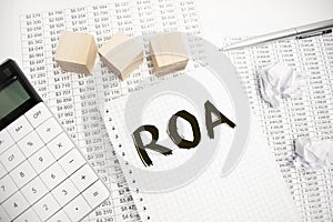 Text ROA on a notebook on diagram and charts with calculator and pen