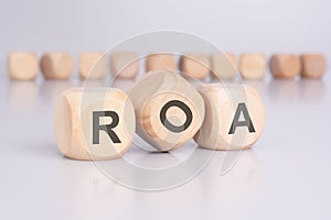 the text 'ROA' - Return On Assets - on wooden cubes, placed on an office desk, suggests a focus on financial
