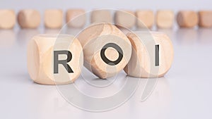 the text 'ROI' - Return on Investment - on wooden cubes, placed on an office desk, suggests a focus on financial