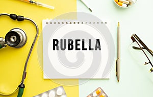 Text RUBELLA on notebook with stethoscope and pen on yellow background.