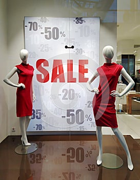 Text Sale on white poster and mannequins standing In store window