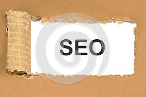 Text SEO on white paper under a torn piece of cardboard