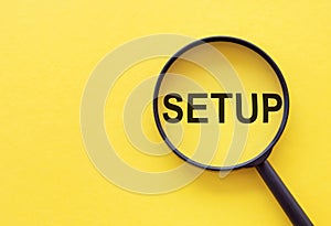 Text SETUP on magnifying glass on yellow desk. Business concept for the analysisner, position, or direction in which something is photo
