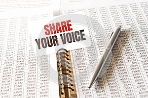 Text SHARE YOUR VOICE on paper card,pen, financial documentation on table - business, banking, finance and investment concept.