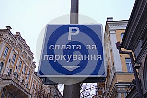 Text on sign: Pay for parking here. Rectangular blue plate with white text. Concept of parking in big city