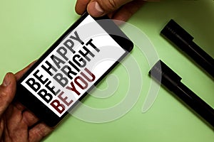Text sign showing Be Happy Be Bright Be You. Conceptual photo Self-confidence good attitude enjoy cheerful Man's hand hold iPhone