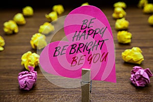 Text sign showing Be Happy Be Bright Be You. Conceptual photo Self-confidence good attitude enjoy cheerful Paperclip hold pink hea