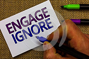 Text sign showing Engage Ignore. Conceptual photo Silent Treatment Manipulative Punishment Sulking Shunning Man hand holding marke photo