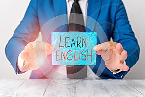 Text sign showing Learn English. Conceptual photo gain or acquire knowledge of speaking and writing English Man holds empty paper