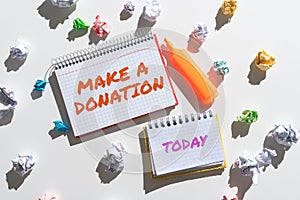 Text sign showing Make A Donation. Concept meaning Donate giving things not used any more to needed showing Notebooks