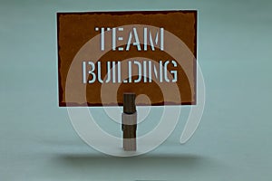 Text sign showing Team Building. Conceptual photo Types of activities used to enhance social relations Clothespin holding orange p