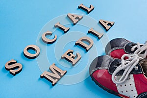 Text social media abstract wooden letters. Blue background with baby sneakers.