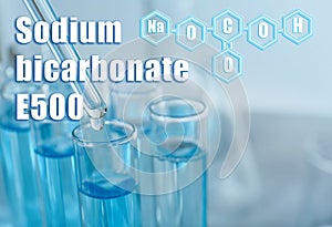 Text Sodium bicarbonate E500 with formula and test tubes on background