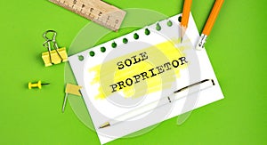 Text SOLE PROPRIETOR sign showing on green background with office tools