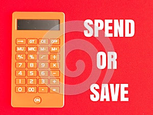 Text SPEND OR SAVE on red background with orange calculator. photo