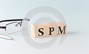 Text SPM - Sales Performance Management - written on the wooden cubes on blue background