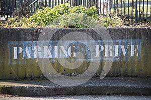 text on stoned wal in french :  parking prive, traduction in english, private parking