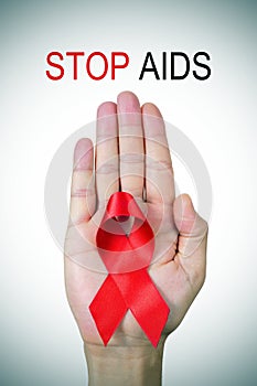 Text stop AIDS and a red ribbon in a man hand