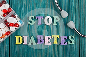 Text & x22;STOP Diabetes& x22; of colored wooden letters, stethoscope and pills