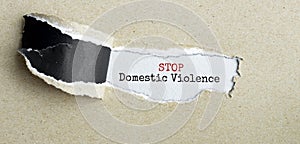 The text STOP Domestic Violence appearing behind torn brown paper photo