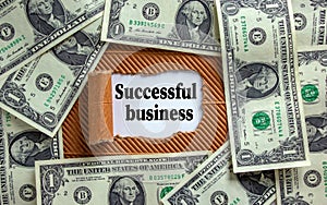 The text `successful business` appearing behind torn brown paper. Dollar bills. Business concept