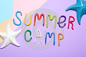 Text SUMMER CAMP made of modelling clay and decorative starfishes on color background