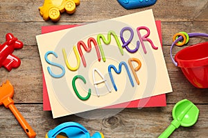 Text SUMMER CAMP made of modelling clay and different sand molds on wooden table