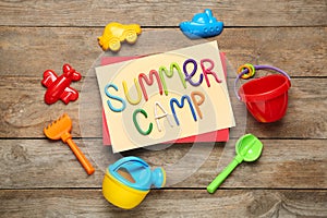 Text SUMMER CAMP made of modelling clay and different sand molds on wooden table