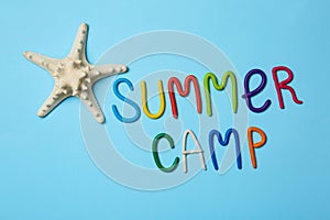 Text SUMMER CAMP made of modelling clay and starfish on color background