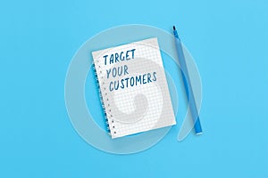 The text Target your customers is written on a notebook page