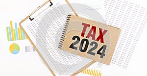 Text TAX 2024 on brown paper notepad on the table with diagram. Business concept