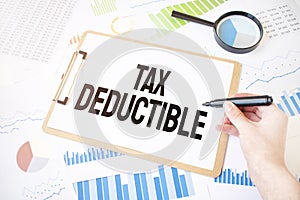 Text TAX DEDUCTIBLE on white paper sheet and marker on businessman hand on the diagram. Business concept