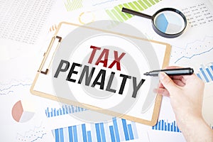 Text TAX PENALTY on white paper sheet and marker on businessman hand on the diagram. Business concept