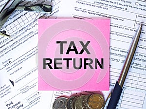 Text Tax Return on note paper with the U.S IRS 1040 form,pen and glasses