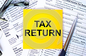 Text Tax Return on note paper with the U.S IRS 1040 form,pen and glasses