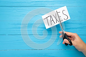 Text of tax and scissors, concept of tax cut on blue background