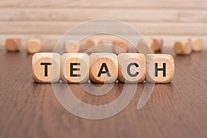 the text 'teach' is written on wooden cubes on a brown background