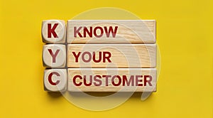 Text text acronym KYC with know your customer written on wooden blocks stacked on a yellow background