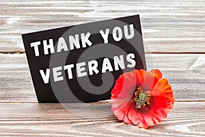 The text thank you veterans written in a chalkboard and red poppy on a rustic wooden background. photo