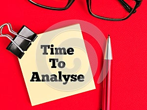 Text Time To Analyse on paper note with stationery isolated on red background.