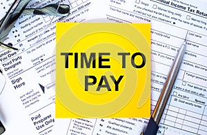 Text Time To Pay on note paper with the U.S IRS 1040 form,pen and glasses