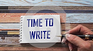 The text TIME TO WRITE is written by a female hand on a notebook.