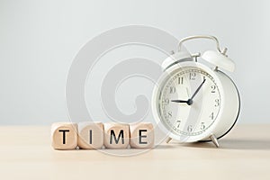 Text `Time` on wooden blocks cube with alarm clock.