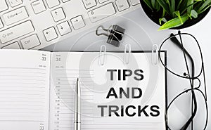 Text TIPS AND TRICKS on white stickers on the notebook with keyboard and glasses