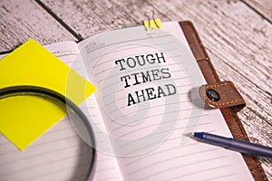 text Tough Times Ahead on black torn paper